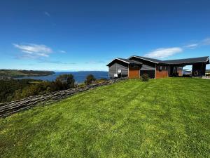 una casa en una colina con un campo verde en Bella casa de campo con panorámica vista al mar, en Dalcahue