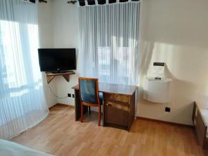 a room with a desk and a tv and a chair at Hôtel La Fontaine in Saint-Imier