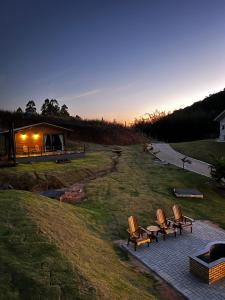 a group of chairs sitting on a patio at sunset at Pousada Vale Das Águias in Jaguaruna