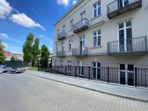 a white building with a fence in front of it at TALIA Apartament Tatarska 4 in Przemyśl