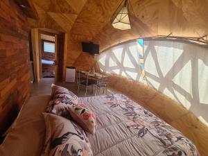 een slaapkamer met een groot bed in een houten hut bij Domos Trayenko in Ralún