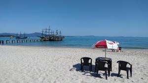 dos sillas y una sombrilla en una playa en Loft encantador a 40 metros do mar., en Florianópolis