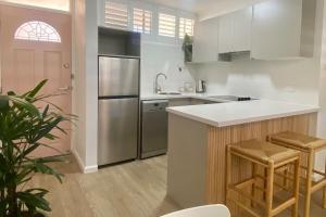 a kitchen with a refrigerator and a counter with stools at Stay Peachy - Kiama in Kiama