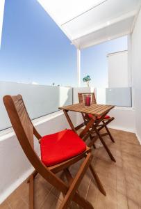 een houten tafel en stoel met een rood kussen bij Luxury Beach Apartments Diama in Playa Honda