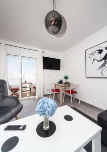 una sala de estar con una mesa con un jarrón de flores. en Luxury Beach Apartments Diama en Playa Honda