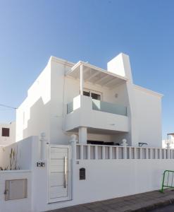 una casa blanca con una puerta y una valla en Luxury Beach Apartments Diama en Playa Honda