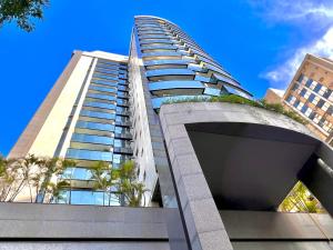 un edificio alto con palmeras delante de un cielo azul en Flat savassi super luxo, en Belo Horizonte