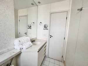 Baño blanco con lavabo y espejo en Flat savassi super luxo, en Belo Horizonte