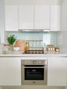 a kitchen with white cabinets and a stainless steel oven at KL COSY CONDO - NEW Stylish home above KL East Mall in Kuala Lumpur