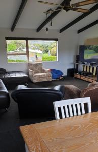 a living room with black furniture and a tv at Hosts on The Coast Holidays On Hardy in Cooks Beach