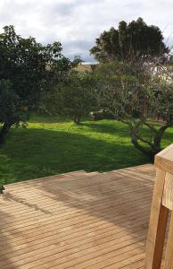 a wooden deck with a bench in a yard at Hosts on The Coast Holidays On Hardy in Cooks Beach