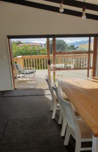 a large wooden table and chairs on a deck at Hosts on The Coast Holidays On Hardy in Cooks Beach