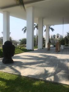 un patio con columnas blancas, césped y palmeras en BONITO DEPARTAMENTO PENINSULA IXTAPA 02 Recámaras, en Ixtapa
