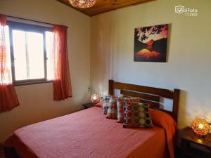 1 dormitorio con cama con sábanas de color naranja y ventana en Un Sueño, en Punta del Diablo