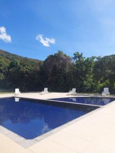 a swimming pool with two chairs and a blue at Suíte no Mirante em Escarpas in Capitólio