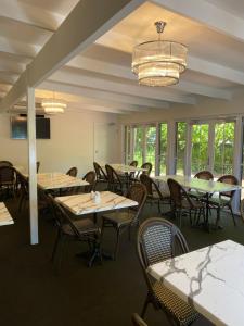 uma sala de jantar com mesas, cadeiras e janelas em Applegum Inn em Toowoomba
