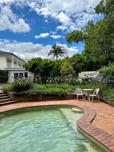 a pool with a pool table and chairs in front of a house at Applegum Inn in Toowoomba