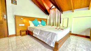 een slaapkamer met een groot wit bed met blauwe kussens bij Masfalhi View Inn in Felidhoo