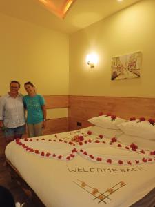 a man and a woman standing next to a large bed at Manta Dhangethi in Dhangethi