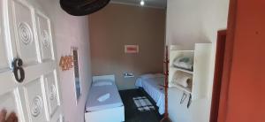 ein kleines Zimmer mit einem Bett und einem Regal in der Unterkunft Pousada da Ponte in Praia de Araçatiba