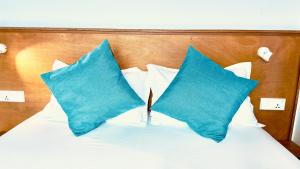 Una cama con almohadas azules encima. en Masfalhi View Inn, en Felidhoo