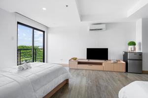 a white bedroom with a bed and a television at Espacio Hotel in Manila