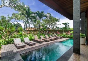 une piscine dans un complexe avec des chaises longues et des arbres dans l'établissement Sarin Ubud Suites by Pramana Villas, à Ubud