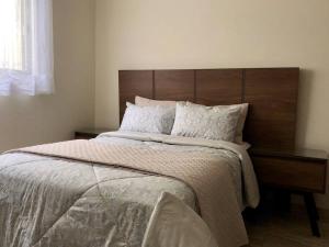 - une chambre avec un grand lit et une tête de lit en bois dans l'établissement Lujoso departamento Winner, à Cuernavaca