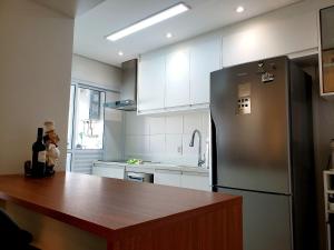 a kitchen with a refrigerator and a wooden counter top at Apê Novo em Sampa Prox do Tietê Plaza in Sao Paulo