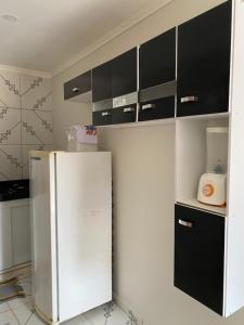 eine Küche mit einem weißen Kühlschrank und schwarzen Schränken in der Unterkunft Apartamento Familiar e aconchegante in Maragogi