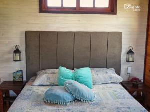 a bed with blue pillows on top of it at UN SUEÑO LOFT in Punta Del Diablo
