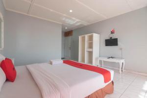 a bedroom with a large bed with a red and white blanket at RedDoorz At Jalan Raya Lembang in Bandung