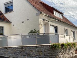 Casa blanca con valla y pared de piedra en Holiday apartment near the Moselle with terrace en Wehr