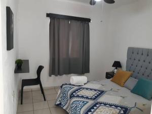 Cómoda Casa a 5 minutos del IMSS في Villa de Alvarez: غرفة نوم بسرير وكرسي ونافذة
