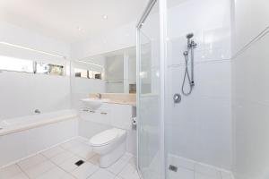 a white bathroom with a toilet and a shower at Marine Drive in Forster +22 photos