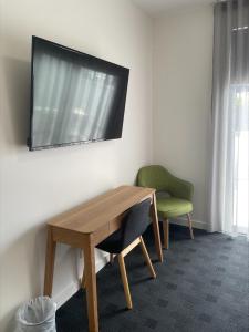 a wooden table with a chair and a television on a wall at Whittlesea Motel 