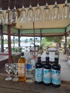 four bottles of alcohol sitting on a table with glasses at Rivergarden Guesthouse and restaurant in Don Det
