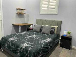 een slaapkamer met een bed met een groen dekbed bij Thirlmere Stayz 4 Bedroom Home with Spa in Thirlmere