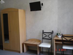 a room with a chair and a table and a tv at Hotel George in Montmélian