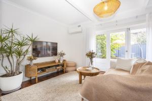 uma sala de estar com um sofá e uma televisão em Cottesloe Coastal Boho Retreat em Perth