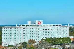 a large white building with a red sign on it at Hotel Nikko Narita in Narita