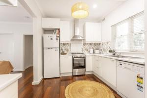 uma cozinha com armários brancos e um frigorífico branco em Cottesloe Coastal Boho Retreat em Perth
