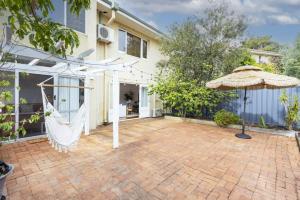 um pátio exterior com um guarda-chuva e uma casa em Cottesloe Coastal Boho Retreat em Perth