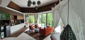 a living room with a couch and chairs and a tv at Cahaya Indah Villas in Ubud