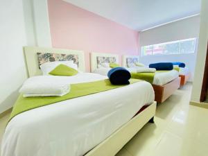 2 camas en una habitación de color rosa y blanco en Hotel Calantha, en Bogotá