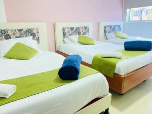 Habitación con 3 camas con sábanas verdes y blancas en Hotel Calantha, en Bogotá