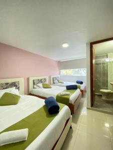3 camas en una habitación con baño en Hotel Calantha, en Bogotá