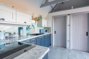 a kitchen with blue and white cabinets and a sink at Raspberry Cottage by Bloom Stays in Great Mongeham