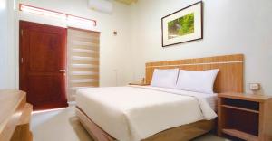 a bedroom with a white bed and a wooden door at Hometown Residence in Bandar Lampung