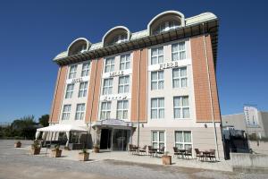 a large building with tables and chairs in front of it at Hotel Delle Fiere in Mozzate